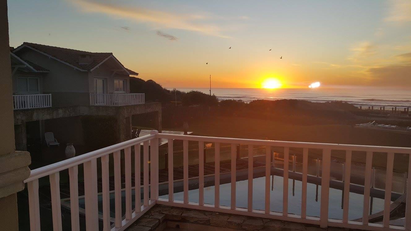 El sol poniéndose sobre el mar, visto desde el balcón de una casa.