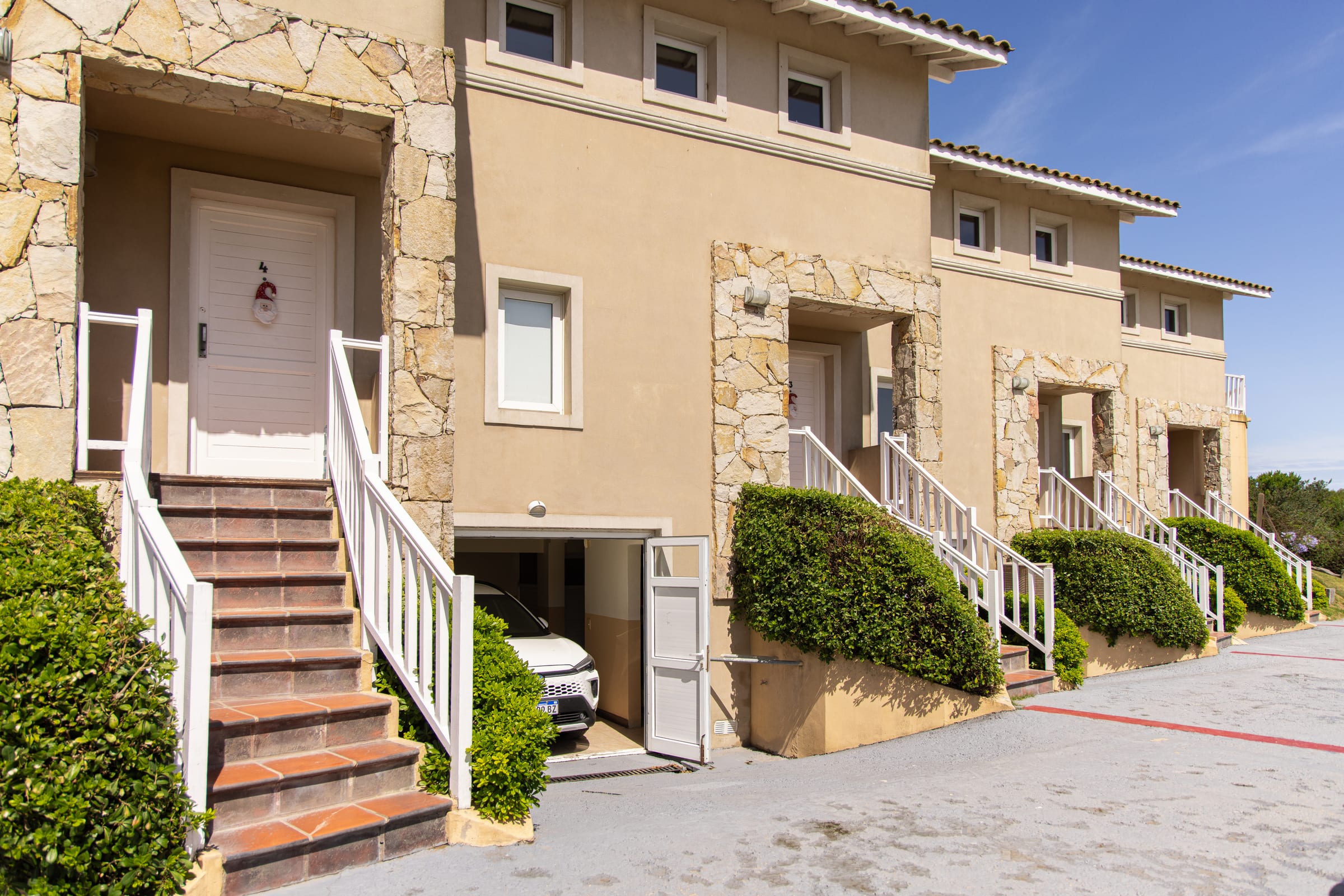Frente de las casas, con la escalera de entrada y la cochera cubierta al costado.