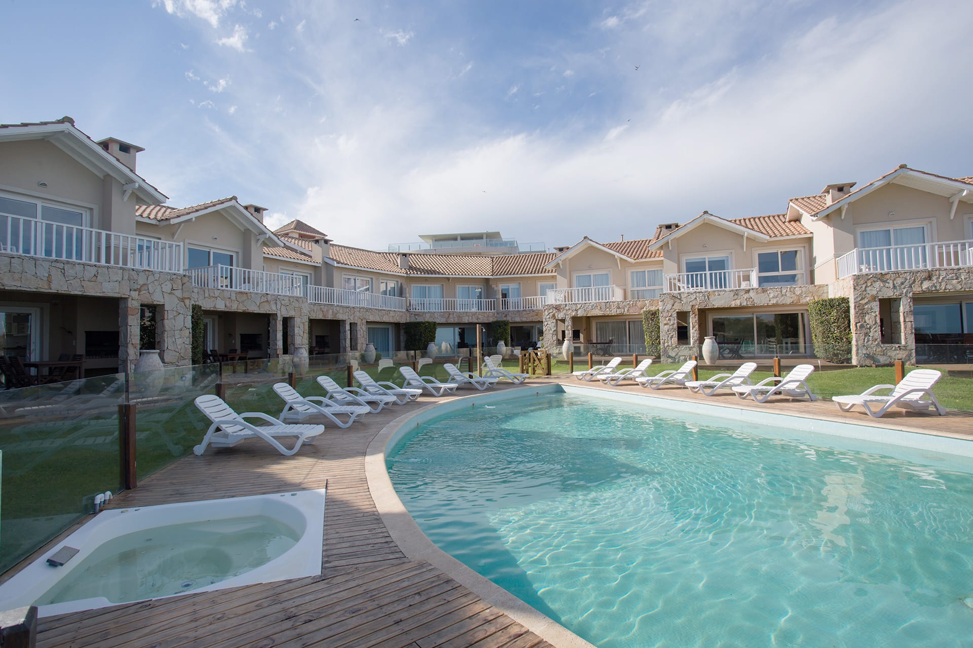 La pileta climatizada con el jacuzzi en primer plano y las casas del complejo al fondo.